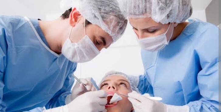 Dental surgeons performing oral surgery procedure on patient